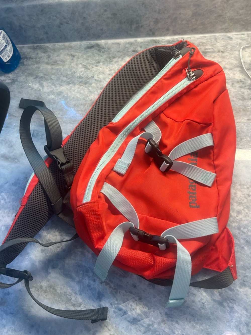 Patagonia Atom orange colorway sling bag with blue Straps